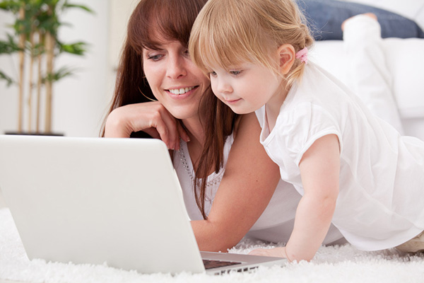 Happy young mother and her daughter using a laptop on Photodune