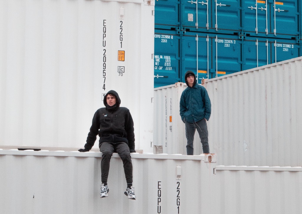 Two guys in hoodies standing on containers