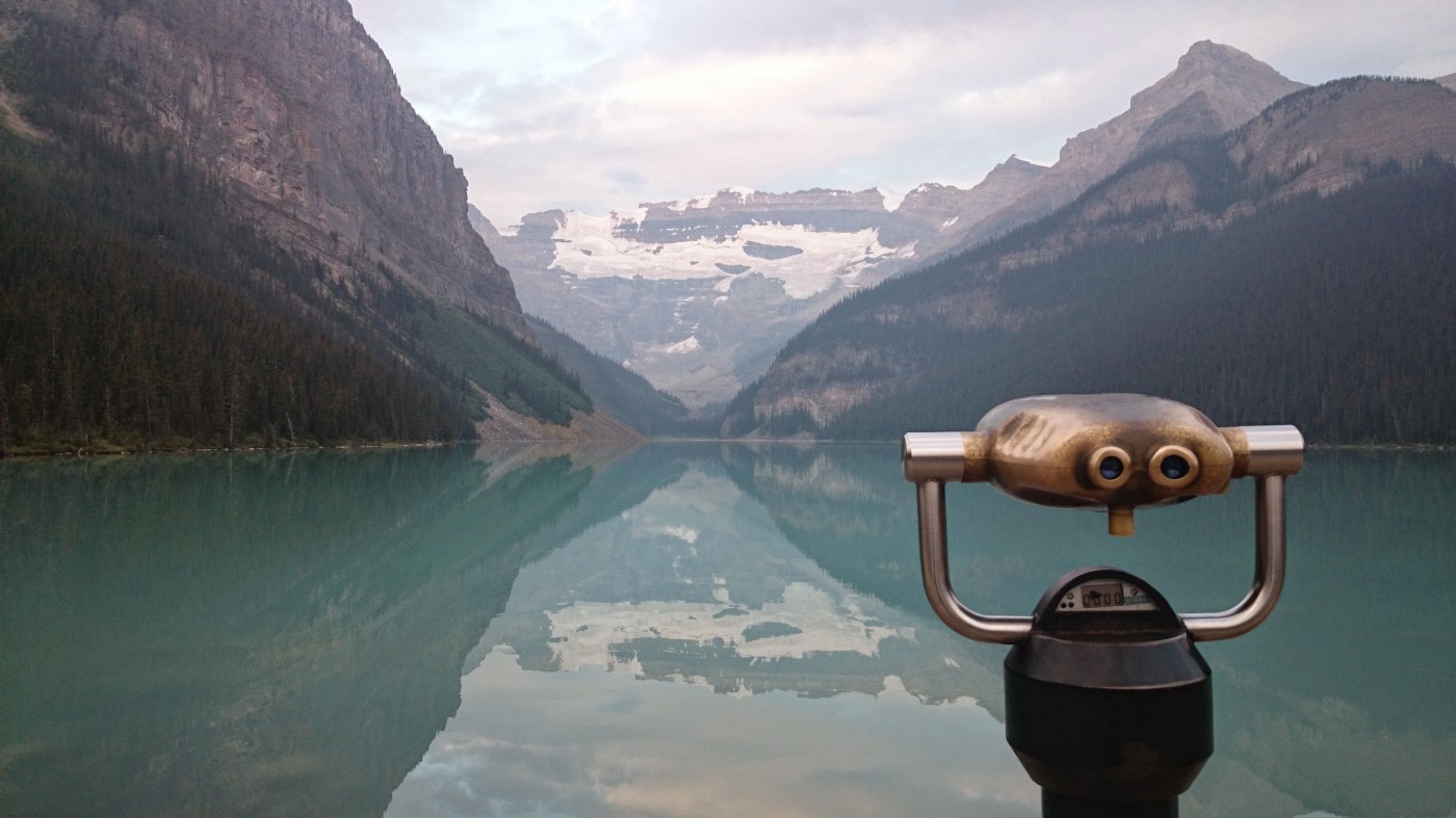 Stationary binoculars in the foreground. Reflecting lake and mountains in the background