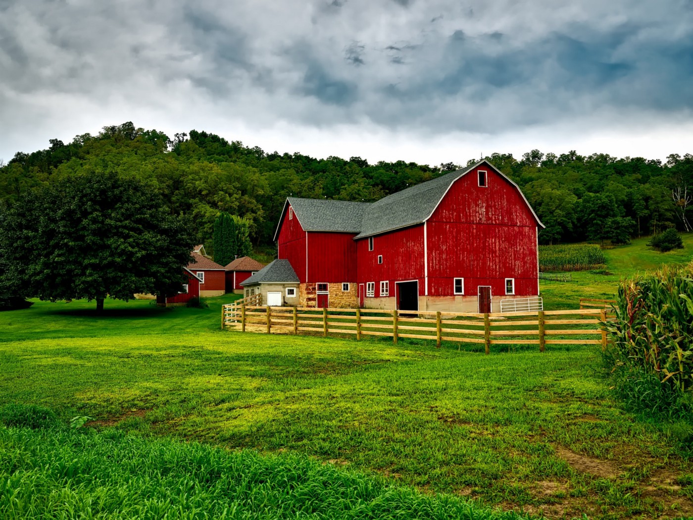 A farmhouse in the middle of a green field. The red barn is need of some paint, and there are a couple of improvements to be made.