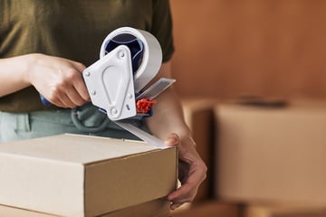 Woman taping a package for shipping.