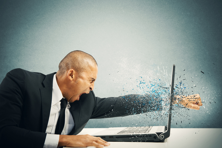 Concept of stress and frustration of a businessman punching his fist through his laptop