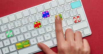 Cropped view of woman with computer keyboard with gift boxes on red background, online christmas for Audacity Mac keyboard shortcuts article.