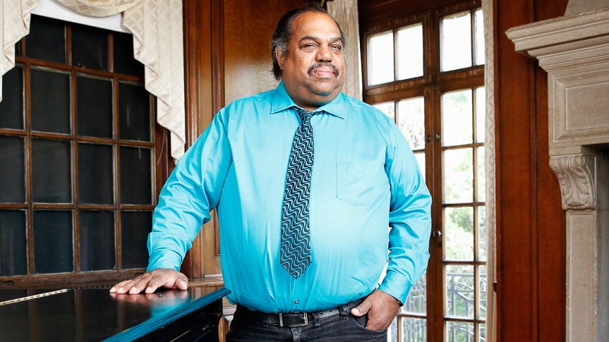 Jazz musician Daryl Davis standing next to his piano