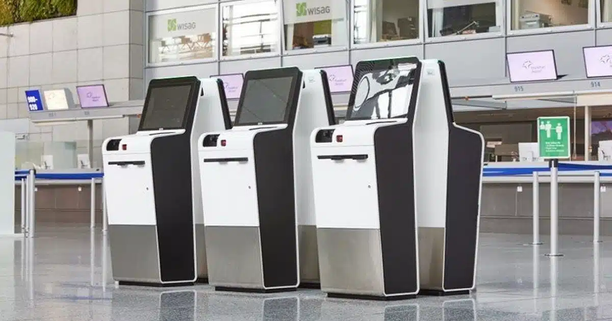 Three self service checkin terminals, with the screen and controls high and tilted upwards. 