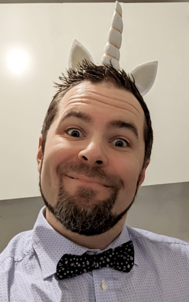 Erik Gustafsson Spagnoli, wearing a white unicorn kids diadem with ears, a light blue dotted shirt with dark blue christmas bowtie, portait photo.