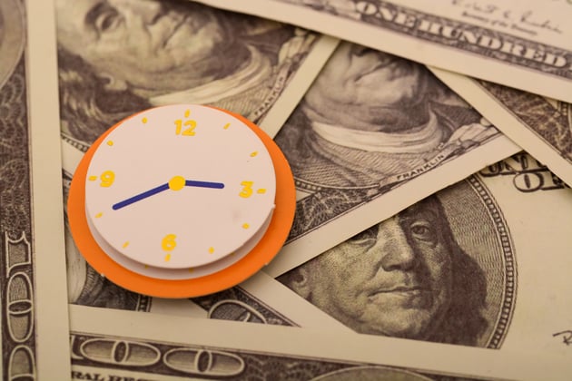 Image with money bills as a background and a clock sitting on top