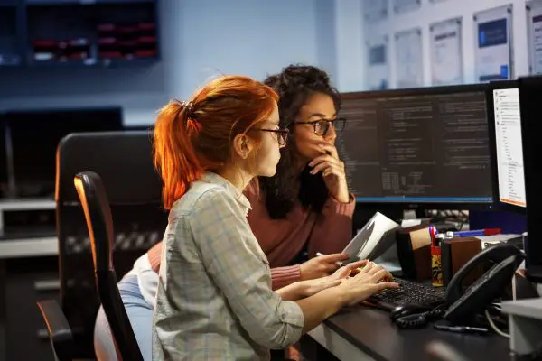 Two developers pair programming in front of a screen.