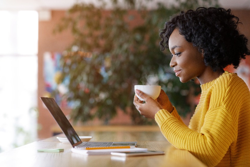 Black lady enjoying morning coffee and checking emails